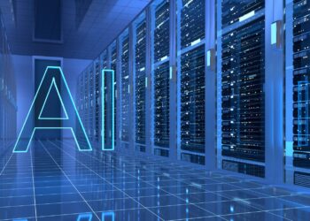 Gambaran ini menunjukkan teks neon bercahaya bertuliskan AI yang melayang di dalam ruang server pusat data modern yang penuh terisi, dengan deretan rak server berkapasitas tinggi berjajar di kedua sisi lantai ubin reflektif, menciptakan suasana komputasi kecerdasan buatan yang futuristik dan berteknologi tinggi.