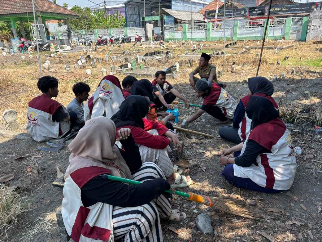 kerja bakti membersihkan area pemakaman. Sejumlah mahasiswa KKN mengenakan seragam merah-putih tampak berkumpul dan beristirahat sejenak setelah melakukan kegiatan kebersihan. (Foto : Dok)